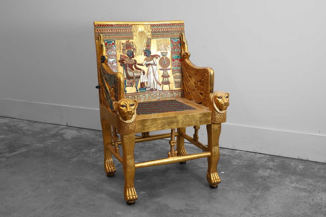 An Egyptian Revival style giltwood armchair, 20th century,: An Egyptian Revival style giltwood armchair, 20th century, in the manner of Liberty & Co, the rectangular back panel decorated in polychrome and parcel-gilt with a pharaonic court scene beneath