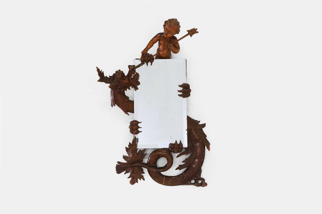 A carved walnut mirror in the manner of Gabriel Viardot, early 20th century, French,: A carved walnut mirror in the manner of Gabriel Viardot, early 20th century, French, the frame in the form of a putto and a dragon, enclosing a rectangular bevelled glass plate (70cm wide, 99cm high)
