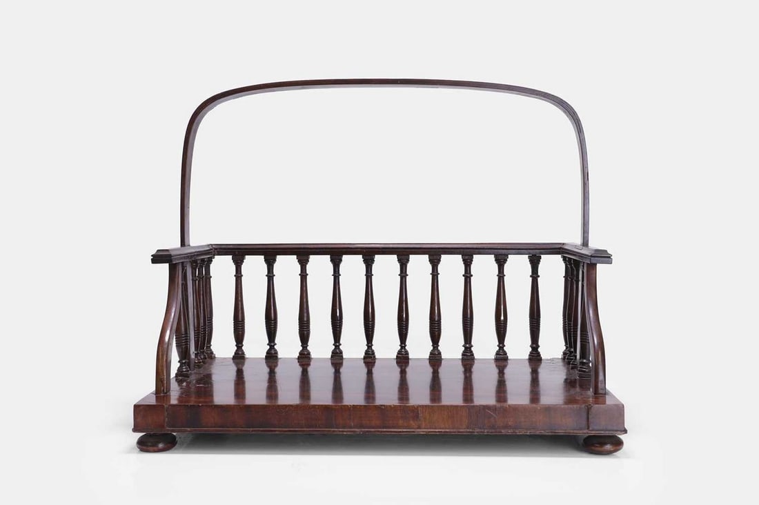 A Regency mahogany book carrier, early 19th century,: A Regency mahogany book carrier, early 19th century, of rectangular form, with a three-quarter spindled gallery and arched top handle, raised on squat bun feet (41cm wide, 27cm deep, 33cm high) Condit