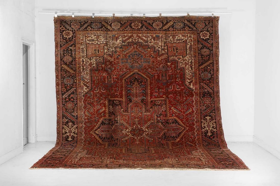 A large Persian Heriz wool carpet, mid-20th century,: A large Persian Heriz wool carpet, mid-20th century, woven with geometric foliate motifs to a red ground (430 x 300cm)