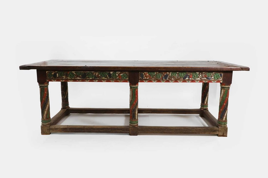 A polychrome-painted oak refectory table, late 16th century and later,: A polychrome-painted oak refectory table, late 16th century and later, the plank top above a frieze carved with fruiting vines, grapes and figures, raised on spiral-fluted column supports united by st