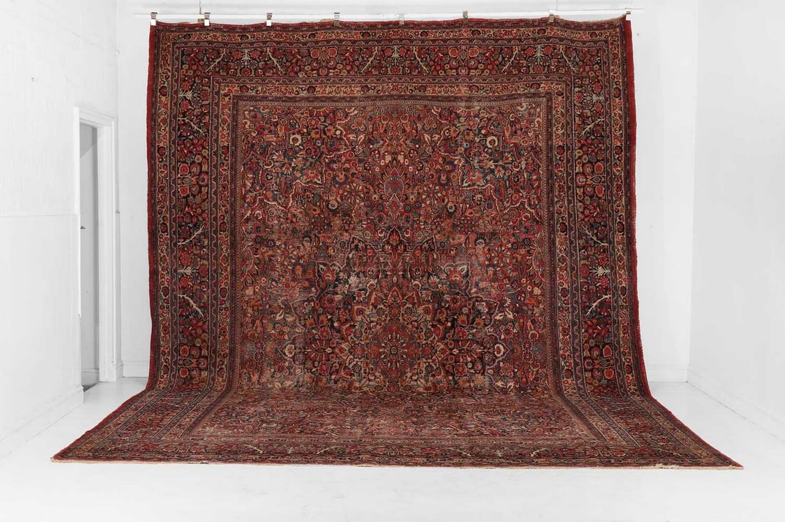 A large Mashad wool carpet, 20th century, Persian,: A large Mashad wool carpet, 20th century, Persian, woven with a stylised foliate medallion to the centre, surrounded by densely applied floral motifs (472 x 346cm) Condition Report: Some fraying to fr