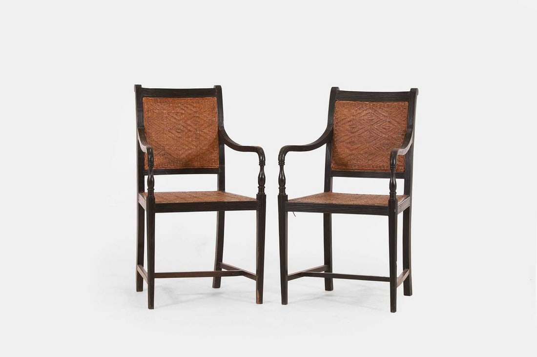 A pair of stained wooden elbow chairs in the Anglo-Indian style, 20th century,: A pair of stained wooden elbow chairs in the Anglo-Indian style, 20th century, each with a reeded frame and a woven rattan back and seat, raised on tapering square supports united by stretchers (53cm
