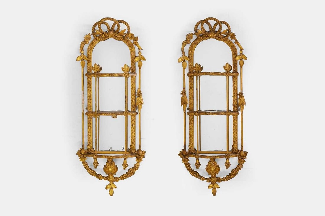 A pair of Victorian gilt-gesso hanging étagères, second half of the 19th century,: A pair of Victorian gilt-gesso hanging étagères, second half of the 19th century, each of multistage form, with scrolling floral and foliate detail, and a mirror back (43cm wide, 16cm deep,