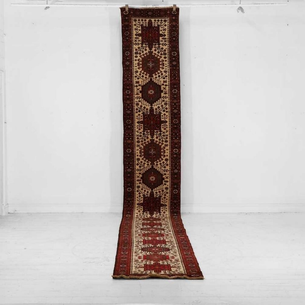 A Heriz wool runner, 20th century,: A Heriz wool runner, 20th century, decorated with repeating geometric medallions to an ivory ground (573 x 75cm)