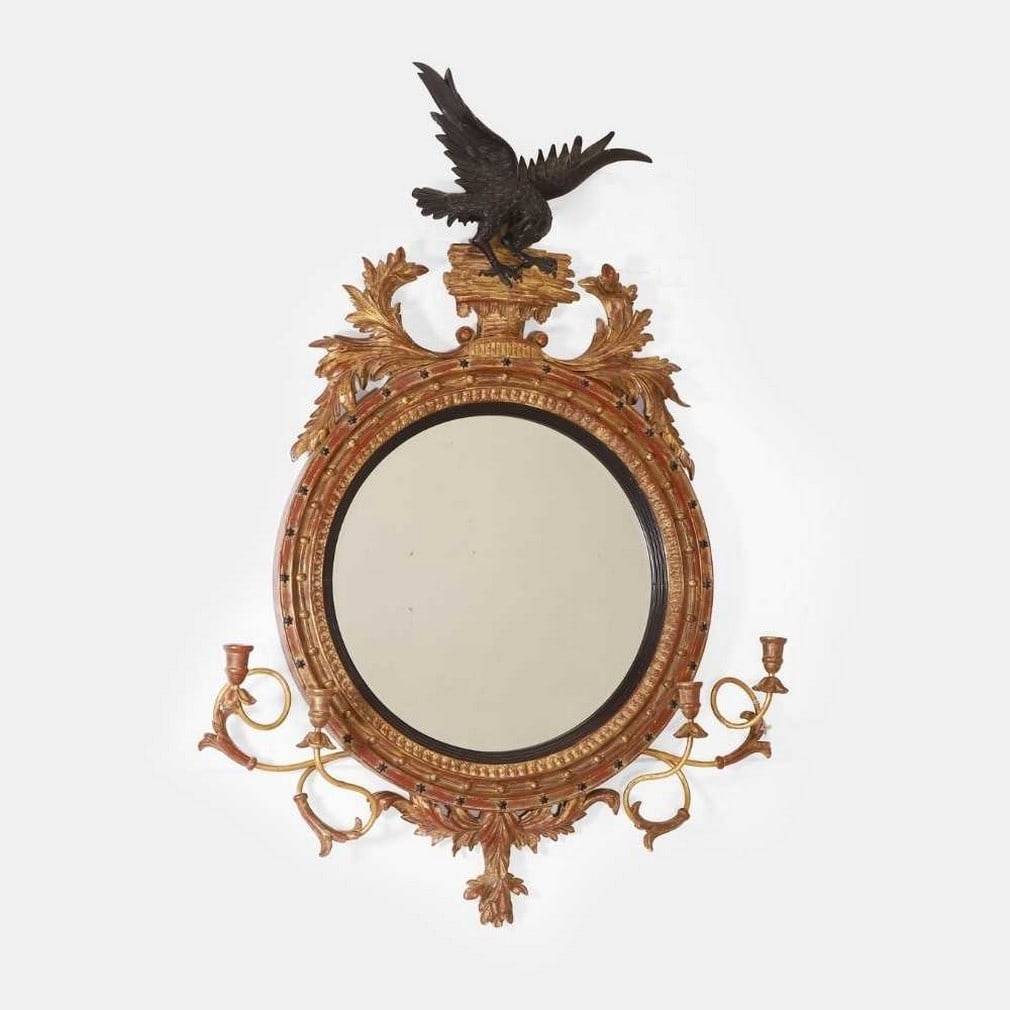 A Regency-style giltwood mirror, 20th century,: A Regency-style giltwood mirror, 20th century, the round frame surmounted by a black-painted eagle crest and set with a pair of scrolling candle arms, enclosing a bevelled glass plate (108cm wide, 154