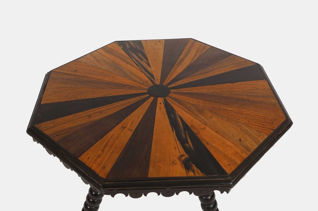 An ebony and specimen wood tripod table, mid to late 19th century, Sri Lankan,: An ebony and specimen wood tripod table, mid to late 19th century, Sri Lankan, the octagonal top inlaid with radiating specimen wood veneers including Macassar, camphorwood, teak, padouk, satinwood an