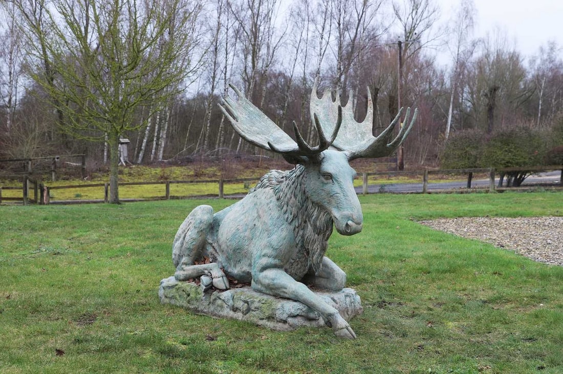 A patinated metal figure of a seated moose, of recent manufacture,: A patinated metal figure of a seated moose, of recent manufacture, modelled in a reclining position on an integrated base (112cm wide, 174cm long, 141cm high)