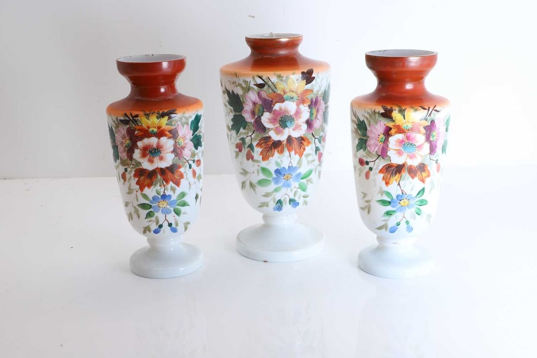 An Edwardian opaline glass garniture, Early 20th century,: An Edwardian opaline glass garniture, Early 20th century, of baluster form, with red to white ombre body, handpainted with a floral bouquet to the main body The largest, 30cm high3Conditio