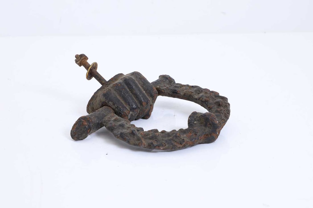 A Victorian 'Wellington' cast iron door knocker, mid to late 19th century,: A Victorian 'Wellington' cast iron door knocker, mid to late 19th century, the circular ring with a central clenched fist grasping a horizontal bar, the ring terminating with lion mask 16cm wide,
