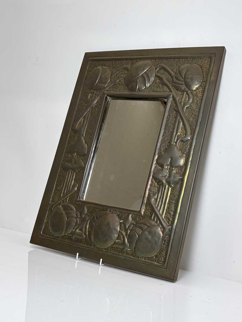 An Arts and Crafts embossed brass wall mirror, circa 1900,: An Arts and Crafts embossed brass wall mirror, circa 1900, possibly Glasgow School, with stylised foliage and flowers, with a plain mirror plate 57.5 x 42cm Condition Report: Fair, good dull