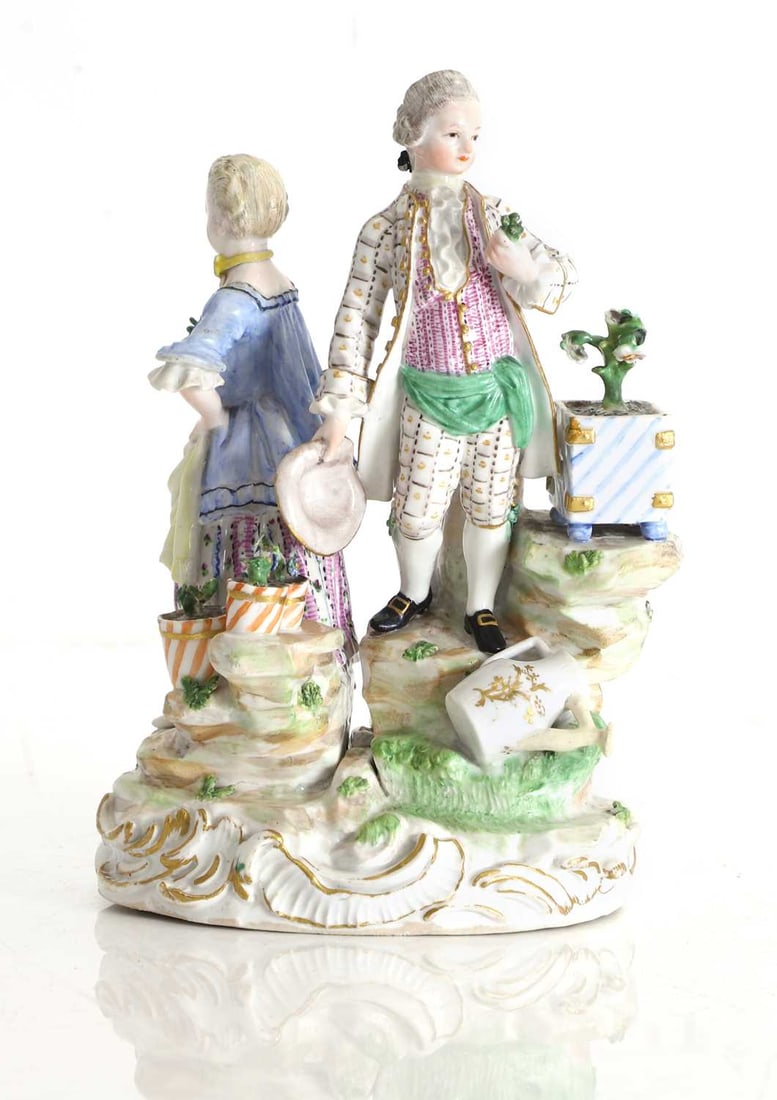 A Meissen figure group of a young couple in 18th century dress, 19th century,: A Meissen figure group of a young couple in 18th century dress, 19th century, modelled as a gallant and lady standing back to back upon a naturalistic mound base with rococo scrollwork edging heighte