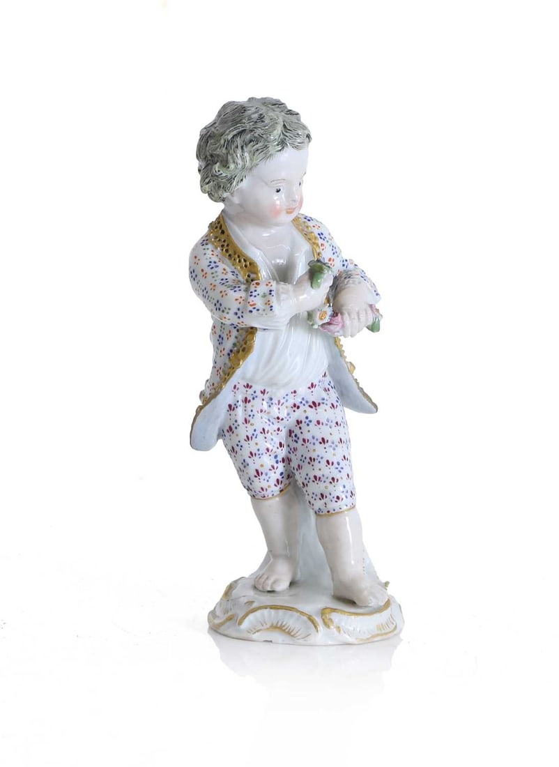 A Meissen figure of a young boy, late 19th century,: A Meissen figure of a young boy, late 19th century, modelled standing barefoot, wearing a white coat, and white breeches, with a floral pattern, holding a garland of flowers, crossed swords mark 