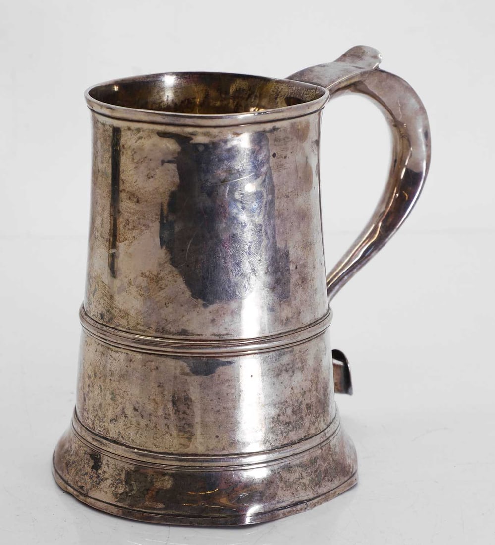 A George III silver tankard,: A George III silver tankard, London, marks worn, of plain form with banding, and shaped handle 15.5cm high, 15.5ozt Condition Report: Knocked and worn, with a gilt interior. Marks rubbed and