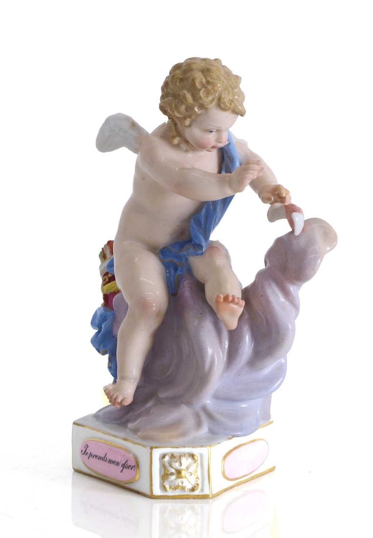 A Meissen figure of a seated Cupid, 19th century,: A Meissen figure of a seated Cupid, 19th century, modelled as a winged Cupid draped in a blue sash, seated on a lilac-tinted cloud, reaching for a winged heart, the triangular base with shamfered