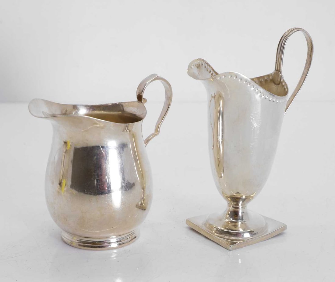 A Georgian style helmet shaped cream jug and another jug,: A Georgian style helmet shaped cream jug and another jug, marks worn, and Sheffield 1934, each of plain form, the helmet jug with impressed rim 15cm and 11.5cm high, 10.6ozt 2 Condition Report: