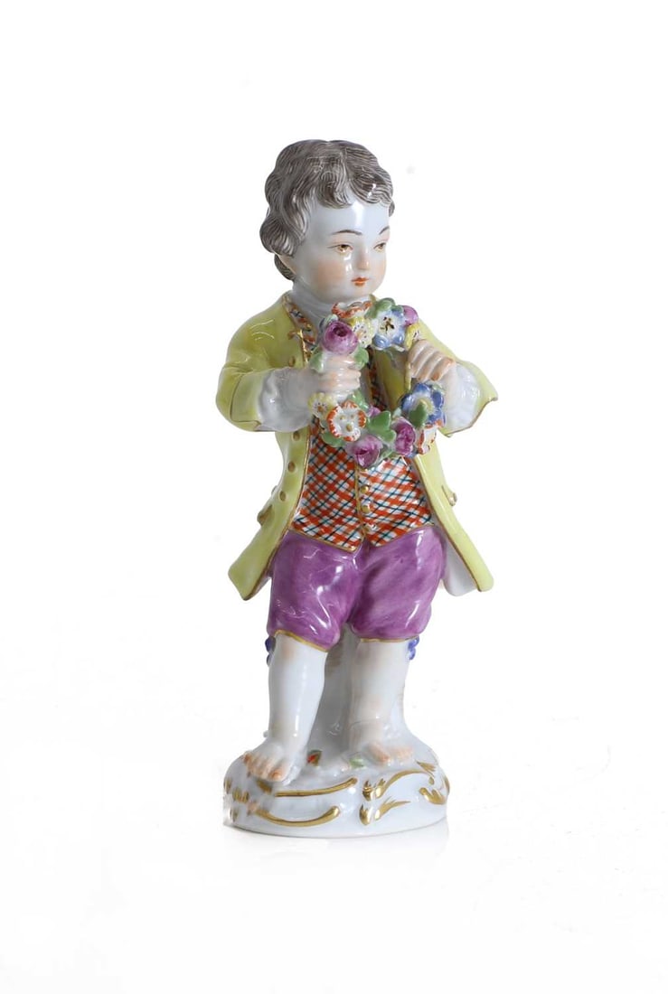 A Meissen figure of a young boy, late 19th century,: A Meissen figure of a young boy, late 19th century, modelled standing barefoot, wearing a yellow coat, check waistcoat, and puce breeches, holding a garland of flowers, crossed swords mark 12cm