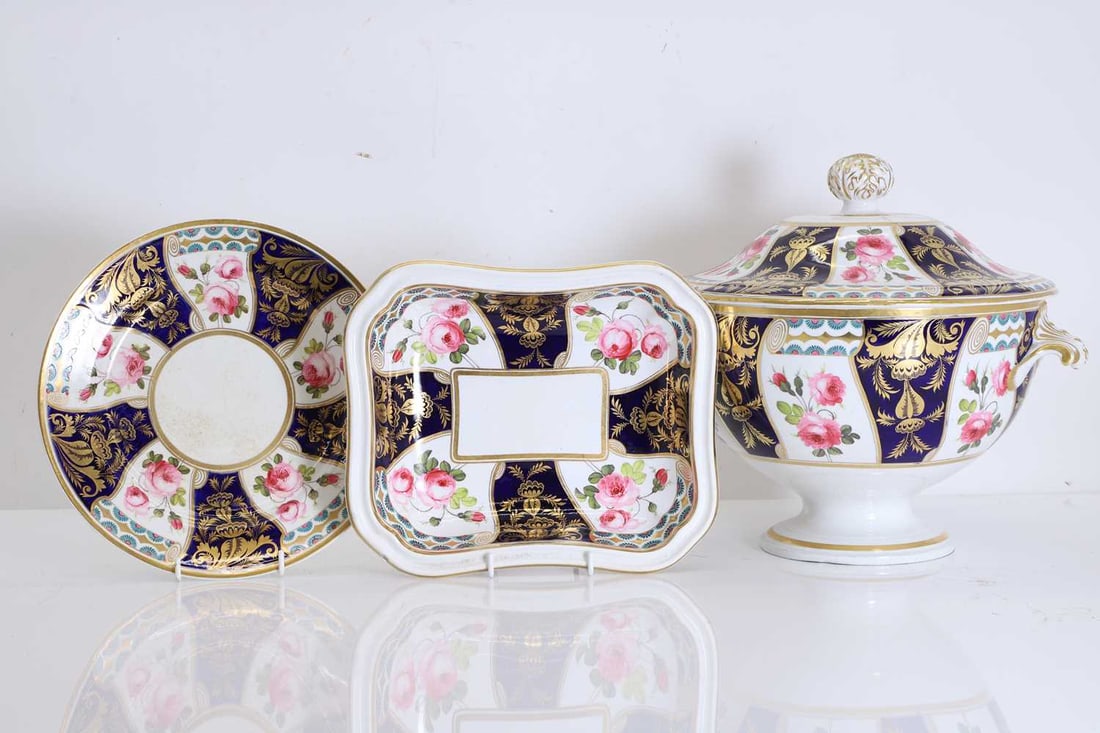 A Derby dinner service, 19th century,: A Derby dinner service, 19th century, by Stevenson & Hancock, decorated with painted pink roses between alternating blue panels enriched with a gilt overlay pattern, the design reserved by a