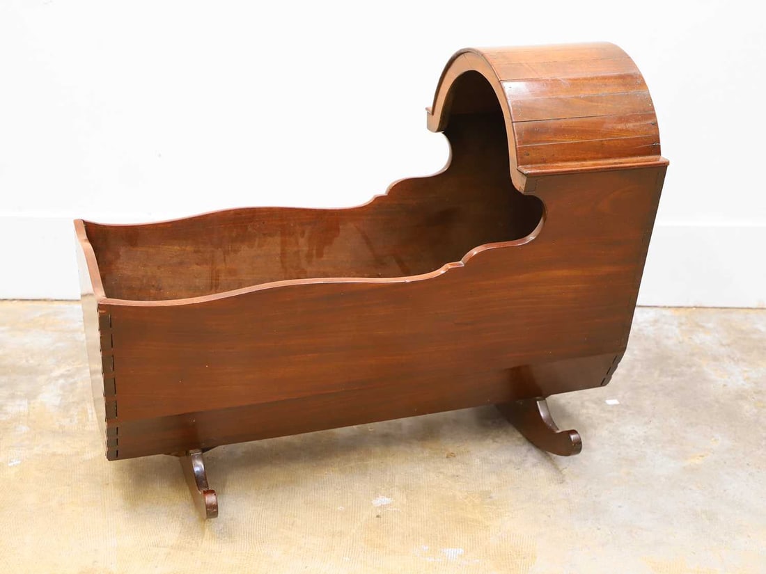 A mahogany crib, 19th century,: A mahogany crib, 19th century, with a hood, on rocker supports, with a straw-filled mattress 92cm wide, 44.5cm deep, 72cm high Condition Report: Fair, usual wear, some splits and wear - colour is