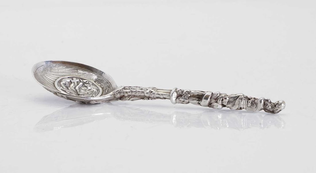 A Dutch silver anointing spoon, probably 18th century,: A Dutch silver anointing spoon, probably 18th century, cast profusely with Christ, angels, god, and further figures to the handle, the surface tests silver 19.5cm long, 5.2ozt