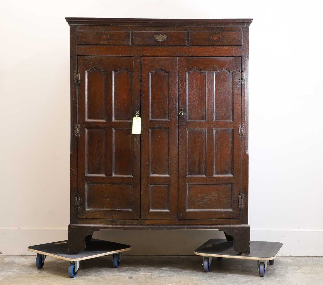 An oak housekeeper's cabinet, 18th century,: An oak housekeeper's cabinet, 18th century, with three faux drawer fronts, over a hinged three-panel cupboard, enclosing a shelf, with chamfered edges, panelled sides, converted to a television or