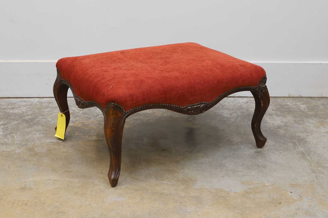 A Victorian carved stool or ottoman, 20th century,: A Victorian carved stool or ottoman, 20th century, the carved stained beech frame, with red velvet upholstery, raised on cabriole legs 80cm wide, 59cm deep, 40cm high Condition Report: Fair