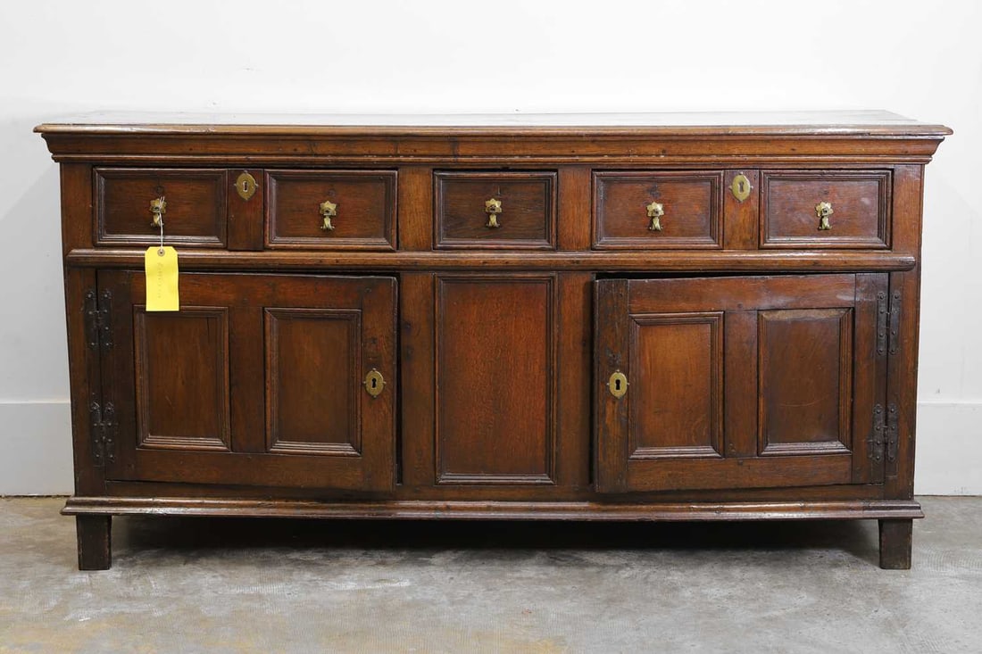 An oak sideboard, 18th century,: An oak sideboard, 18th century, with three panelled drawers and two cupboards, with floral escutcheon and drop handles 168cm wide, 48cm deep, 85cm high Condition Report: Wear commensurate with