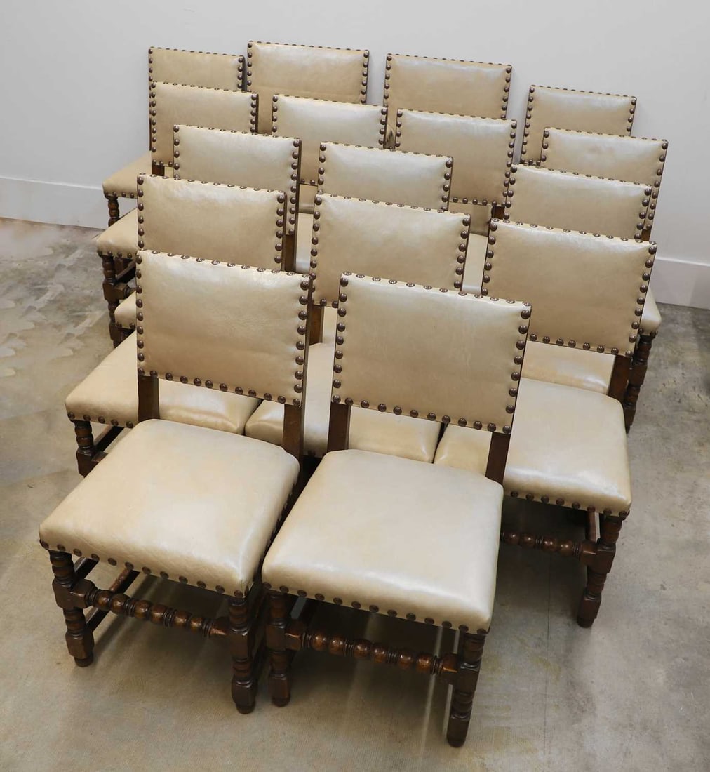 A set of sixteen oak dining chairs, early 20th century,: A set of sixteen oak dining chairs, early 20th century, comprising a pair of elbow chairs, and fourteen singles chairs, each with a rectangular padded back and seat upholstered in buff leather and
