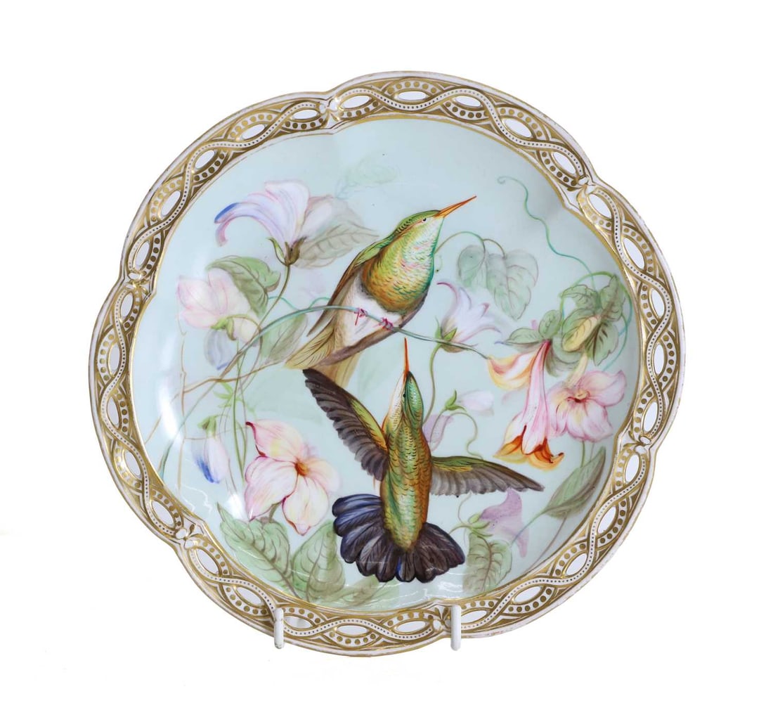 A French porcelain comport, 19th century,: A French porcelain comport, 19th century, decorated with hummingbirds amongst foliage, with a pierced twisted border, terminating on a pedestal base with three square feet 23.5cm diamater, 6.2cm