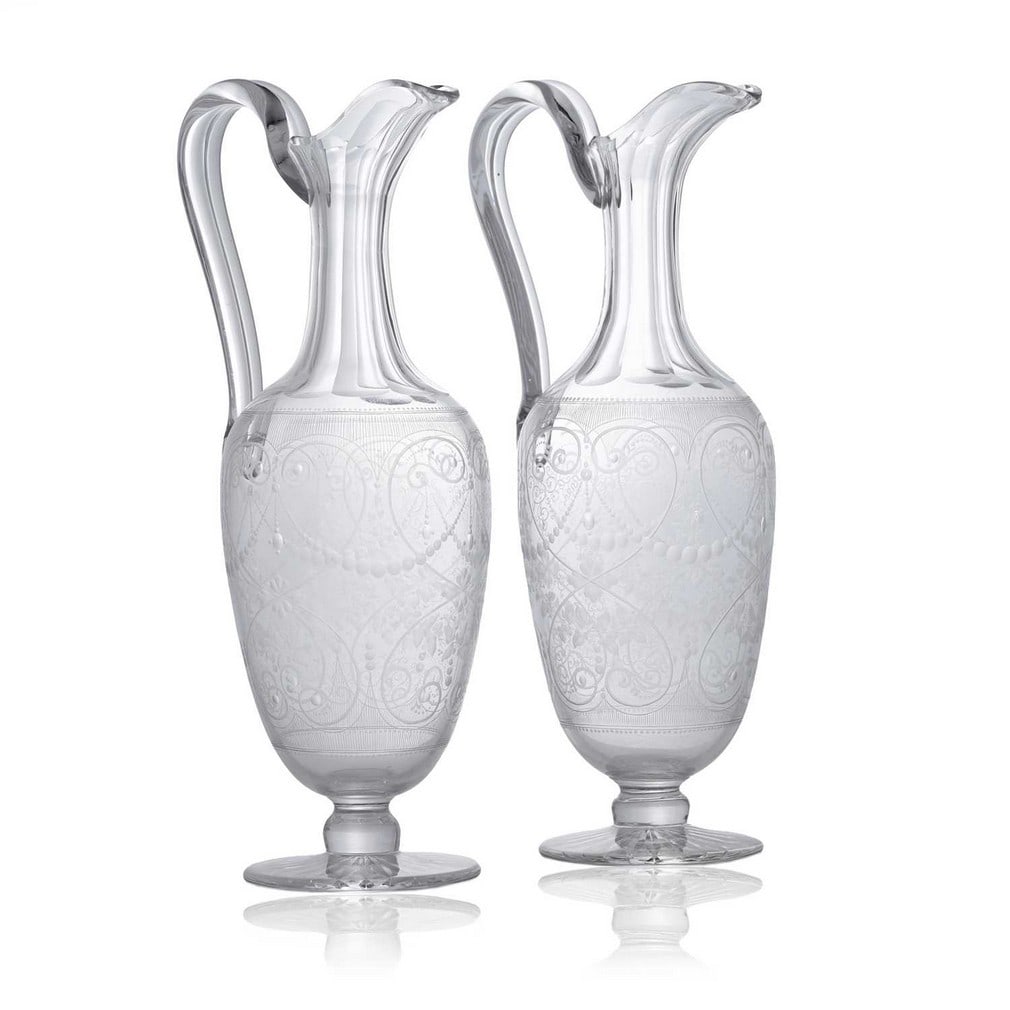 A pair of engraved glass claret jugs, circa 1870, Stourbridge,: A pair of engraved glass claret jugs, circa 1870, Stourbridge, each of ovoid form with an applied pump handle, engraved with scrolling floral motifs (12cm wide, 10cm deep, 30cm high) (2) Provenance: F