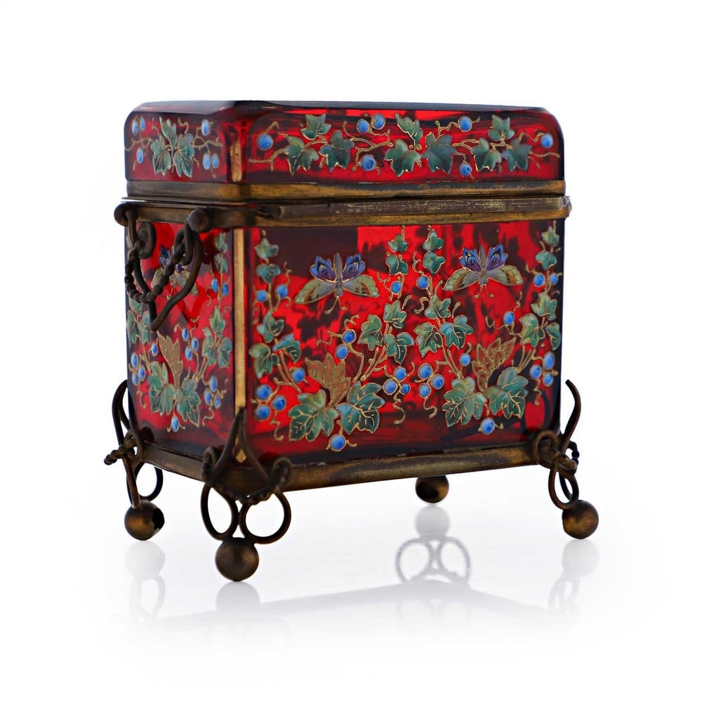 An enamelled glass casket, late 19th century, Bohemian,: An enamelled glass casket, late 19th century, Bohemian, of rounded rectangular form, with applied brass mounts, enamelled with birds and butterflies amongst foliage to a ruby ground, partial paper lab