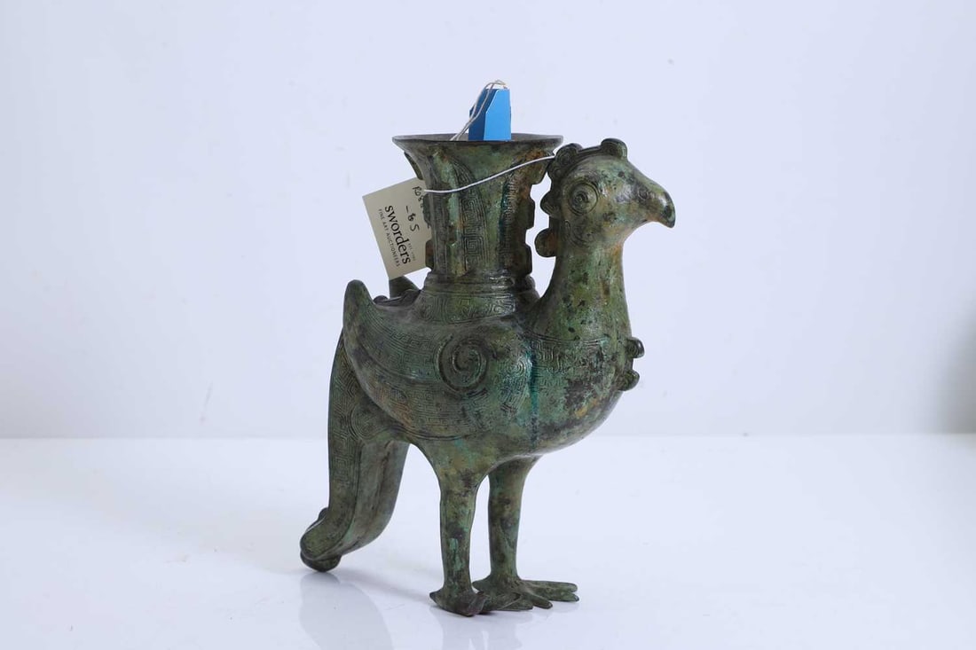 A Chinese bronze 'phoenix' wine vessel,: A Chinese bronze 'phoenix' wine vessel, modelled in the archaic style, the body decorated with key scroll patterns, a trumpet-shaped vase emerging from the back 22cm high Condition Report: Some