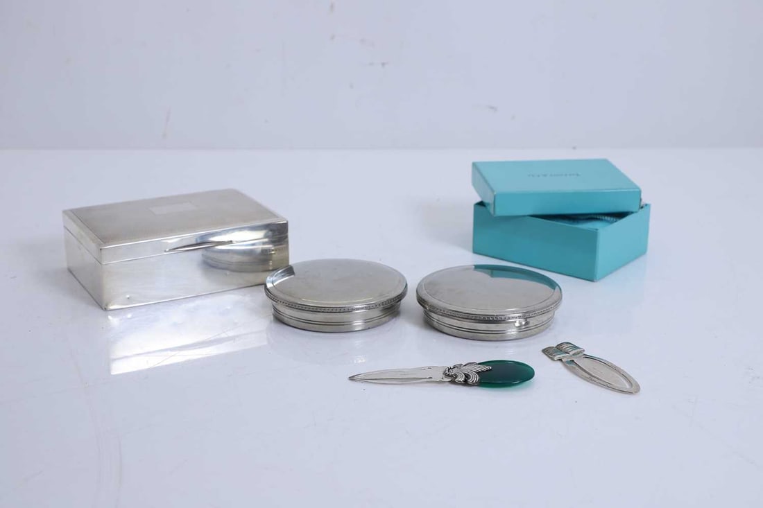 Two Tiffany & Co circular jars and covers,: Two Tiffany & Co circular jars and covers, pewter, with stamped marks to the base, together with three silver bookmarks, one by retailed by Tiffany & Co, shaped as a present, with dust cover and
