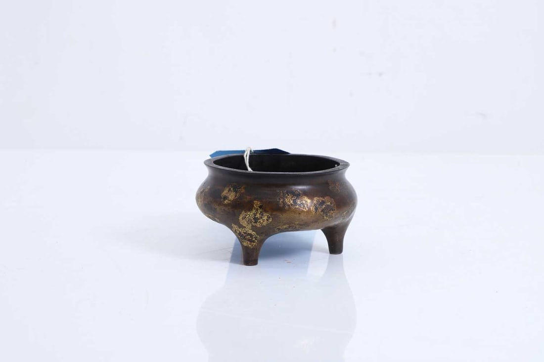 A Chinese bronze incense burner, 20th century,: A Chinese bronze incense burner, 20th century, with gilt splashed decoration and six-character mark to the base 6.4cm high, 11cm diameter Condition Report: Some minor dents to the rim and sides.