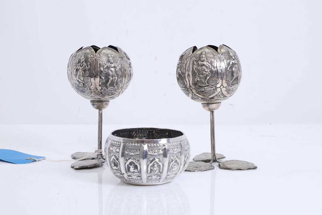 A pair of silvered metal goblets, circa 1920, South Indian, Bombay (Mumbai),: A pair of silvered metal goblets, circa 1920, South Indian, Bombay (Mumbai), each with engraved leaf shaped supports, the spherical bowl cast in relief with figures of Vishnu in an archway, and a sil