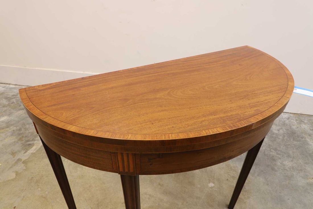 A George III mahogany and satinwood card table, third quarter of the 18th century,: A George III mahogany and satinwood card table, third quarter of the 18th century, the crossbanded and line-inlaid top of demi-lune shaped form, opening to a green baize-lined playing surface above