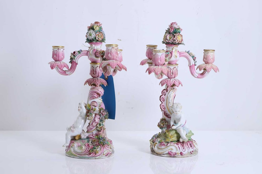 Two Dresden style candlebra, 20th century,: Two Dresden style candlebra, 20th century, the boucade base with putti sat on the floor, below three-branched candle holder 22cm wide, 34.5cm high 2 Condition Report: Chipping to the relief