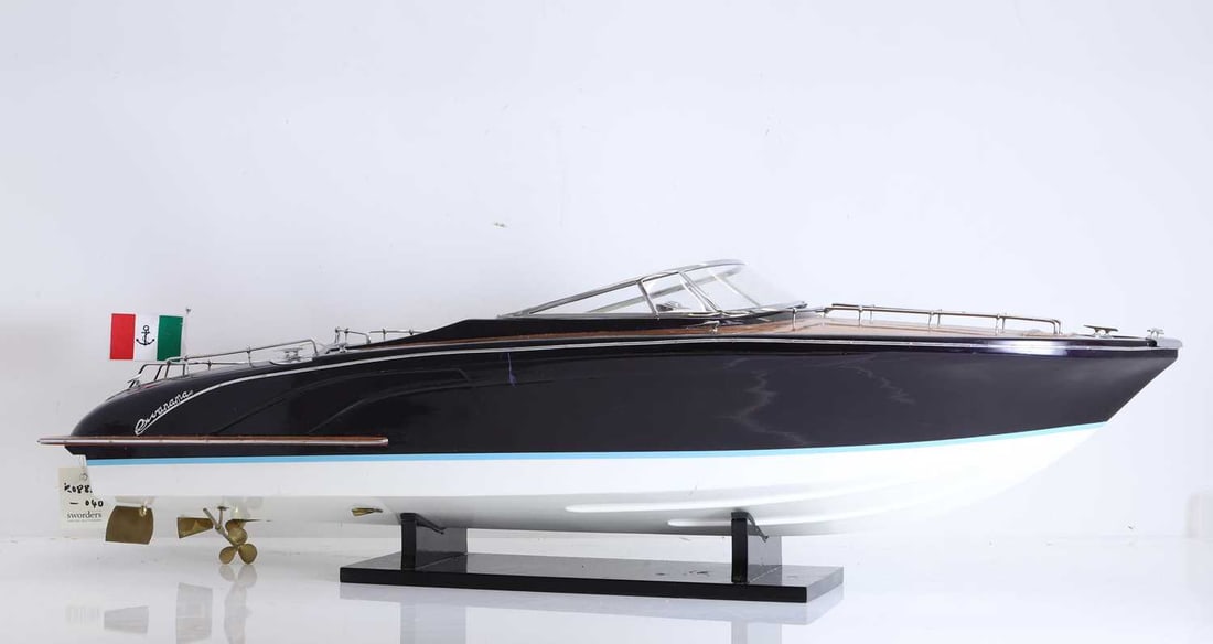 A model of a Riva 'RIVERAMA' speedboat, of modern manufacture,: A model of a Riva 'RIVERAMA' speedboat, of modern manufacture, with a white and blue painted hull and a black main body, the interior upholstered in white leather, with a black wooden stand 92cm