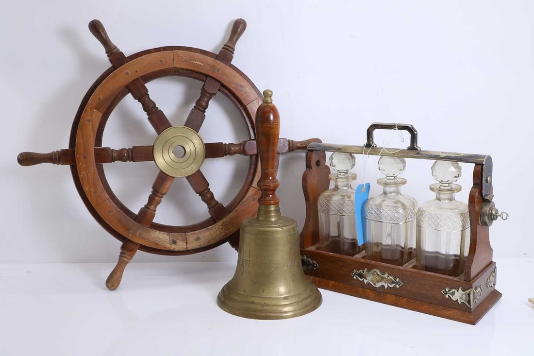 A three bottle tantalus, a ships wheel and a bell, 20th century,: A three bottle tantalus, a ships wheel and a bell, 20th century, silver-plated and brass-mounted, the bell engraved 'Captain's Table', 39cm wide, wheel, 63cm, bell, 41cm high 3 Condition Report: