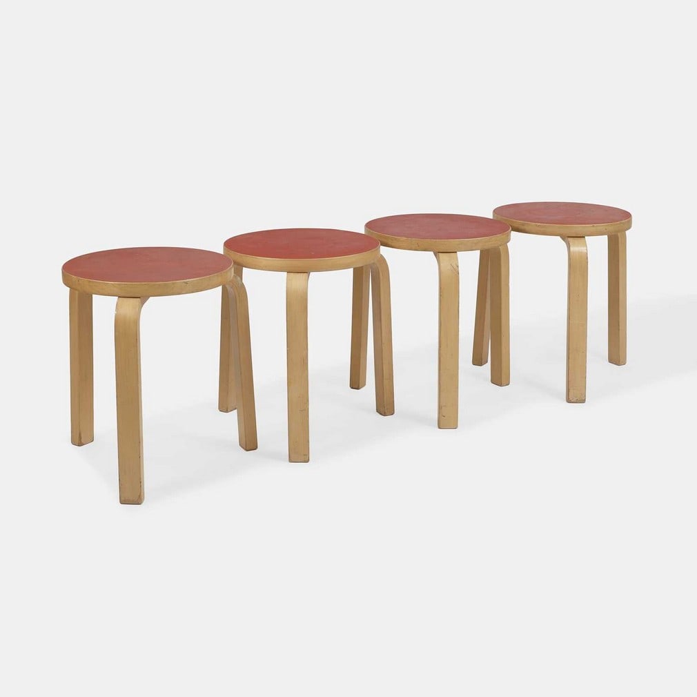 Alvar Aalto (Finnish, 1898-1976), a set of four '60' stools,: Alvar Aalto (Finnish, 1898-1976), a set of four '60' stools, originally designed in 1933, manufactured circa 1960s, each of birch plywood with a red laminate top (40cm diameter, 45cm high) (4)