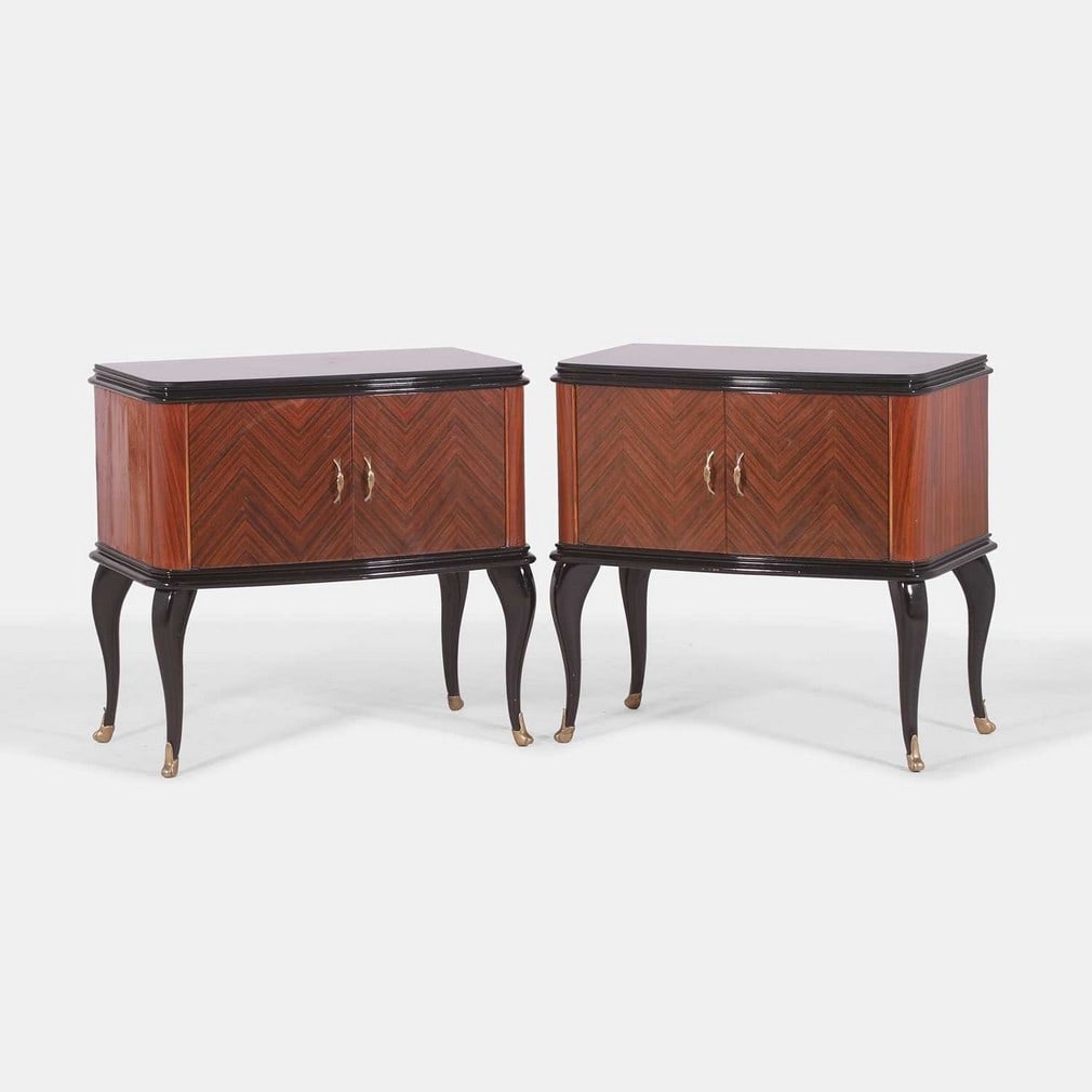 Italian, a pair of mahogany bedside tables,: Italian, a pair of mahogany bedside tables, circa 1950, each with an ebonised top, over a pair of quarter-veneered doors with brass demilune-form handles, raised on ebonised cabriole legs with brass c