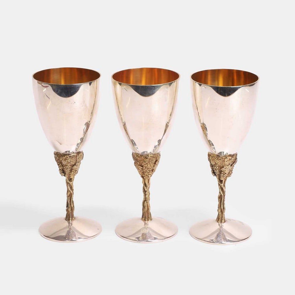 Stuart Devlin (Australian-British, 1931-2018), three silver and silver-gilt grapevine goblets,: Stuart Devlin (Australian-British, 1931-2018), three silver and silver-gilt grapevine goblets, two dated London, 1977, and another, dated 1978, each polished silver cup with a silver-gilt interior, ra
