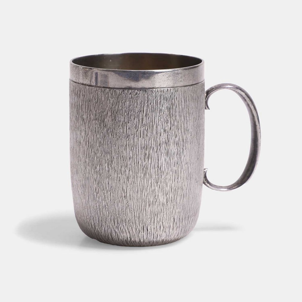 ▲ Christopher Nigel Lawrence (b.1936), a silver and silver-gilt mug,: ▲ Christopher Nigel Lawrence (b.1936), a silver and silver-gilt mug, London, 1975, of cylindrical form, with textured sides, a polished silver band to the rim, rounded handle and silver-gilt int