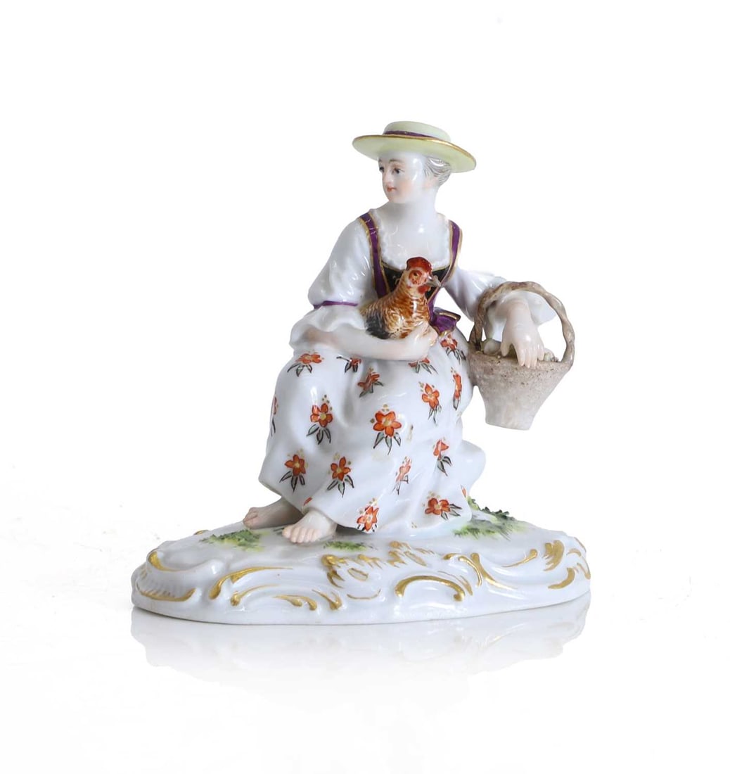 A Meissen figure of a seated lady with a hen and basket of eggs, late 19th century,: A Meissen figure of a seated lady with a hen and basket of eggs, late 19th century, modelled as a lady seated barefoot upon a rococo-moulded base decorated with gilt, wearing a broad brimmed hat, and