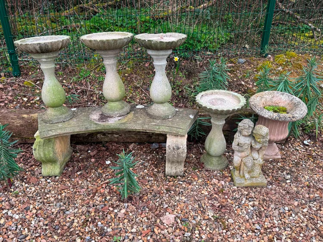 A collection of reconstituted garden items, 20th century,: A collection of reconstituted garden items, 20th century, comprising a set of four pedestal stands, a concave bench, an urn and a figure of cherubs Stands, 55,5cm high, 35cm diameter, seat, 120cm