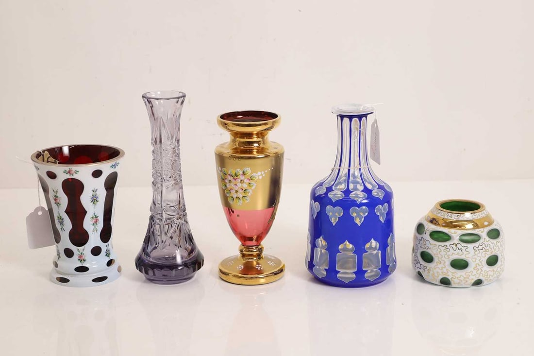 A collection of Czech cased and cut glass items, 20th century: A collection of Czech cased and cut glass items, 20th century comprising a blue bottle vase, cut with trefoil motifs, a white over ruby vase, with enamelled floral decoration, a squat vase, cased in