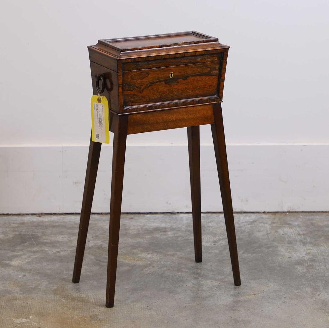 A rosewood tea caddy on stand, late 19th century,: A rosewood tea caddy on stand, late 19th century, the sarcopaghus-shaped box, with two internal lidded lift-out compartments, with hoop handles, on fixed stand 32cm wide, 18cm deep, 65cm highConditio