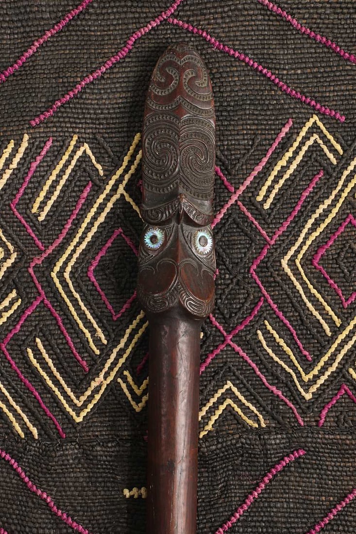 A Maori taiaha staff, 19th century,: A Maori taiaha staff, 19th century, New Zealand, having a stylised tiki head with mother-of-pearl eyes, over a plain shaft and spatulate terminal 170cm long Condition Report: One or two small