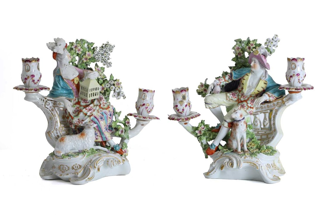 A pair of continental figural candelabra, circa 1880,: A pair of continental figural candelabra, circa 1880, in the manner of Derby, each modelled as an elegant gallant and companion seated upon a rococo scroll-moulded base enriched in gilt, before