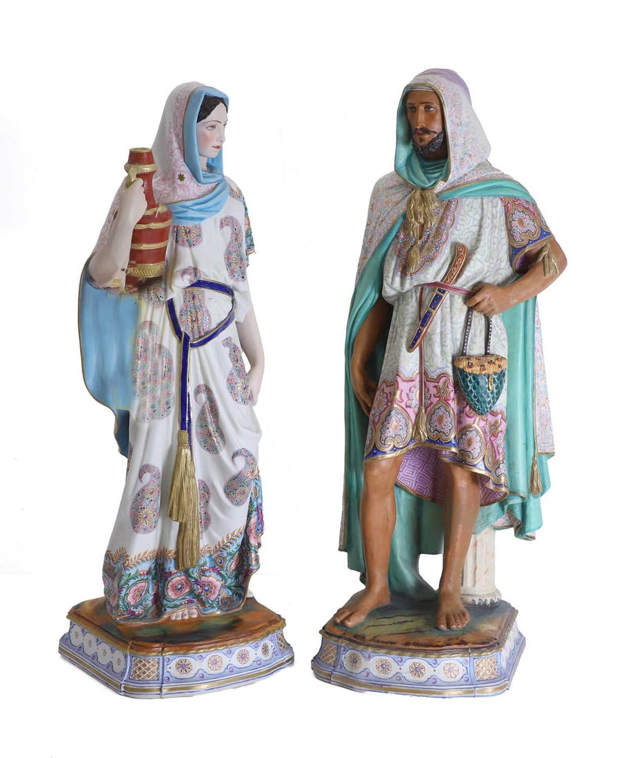A pair of Continental bisque figures, late 19th century,: A pair of Continental bisque figures, late 19th century, each modelled standing and barefoot upon a shaped rectangular base painted with a rocky landscape, the lady holding a red ewer at her